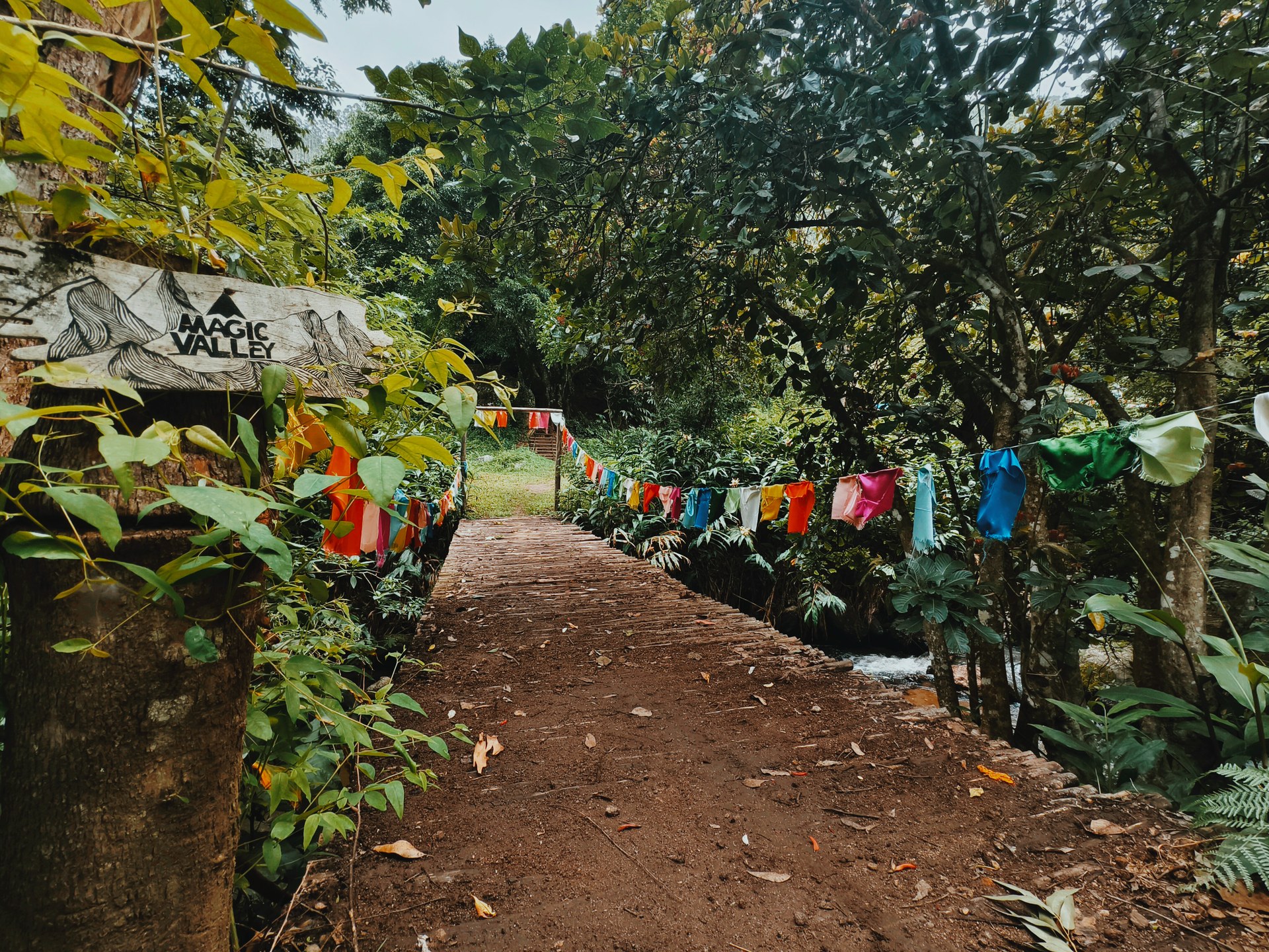 Colourful prayer flags over a wooden bridge at Magic Valley entrance